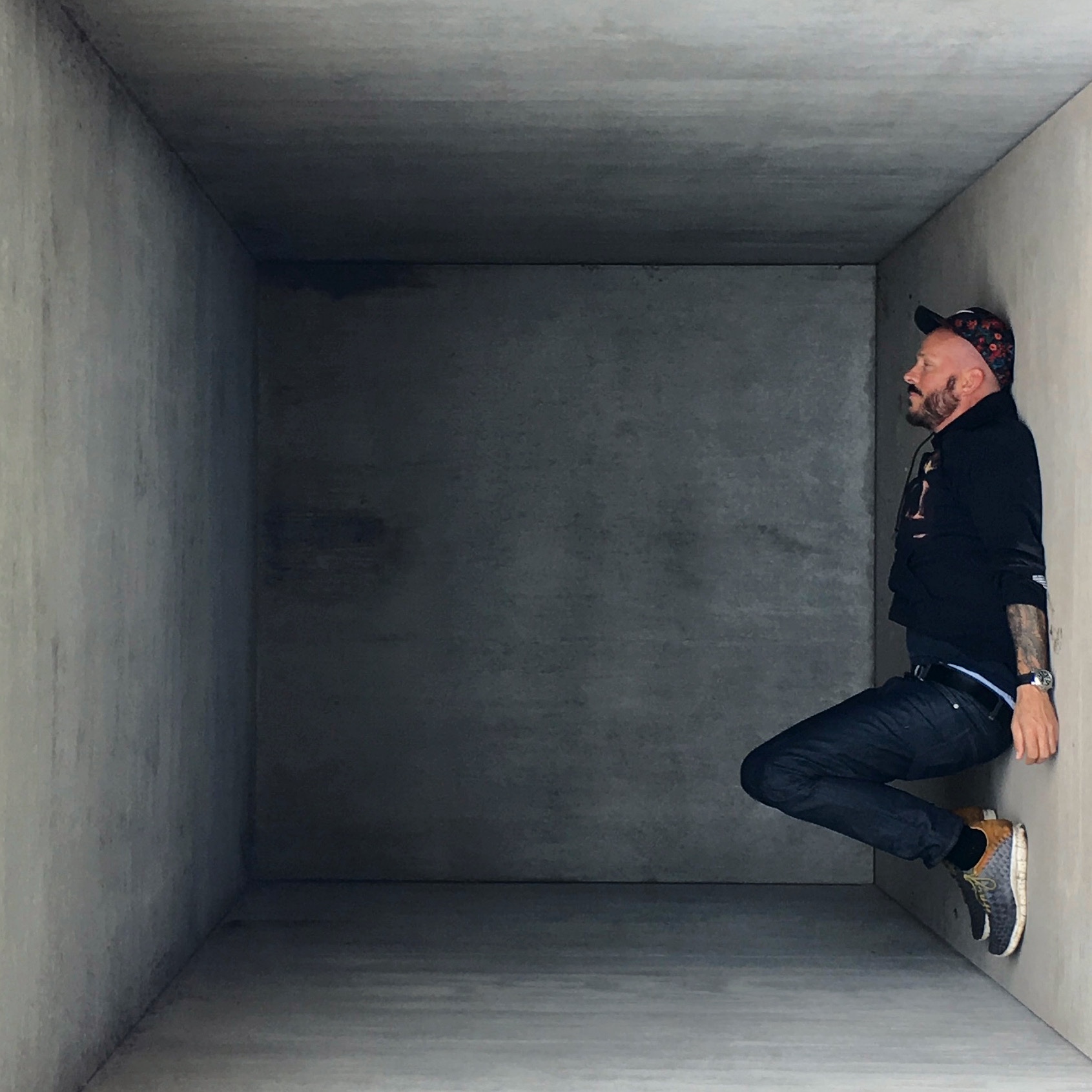 Kevin Kollenda at rest inside a bare concrete room, sitting sideways against its wall